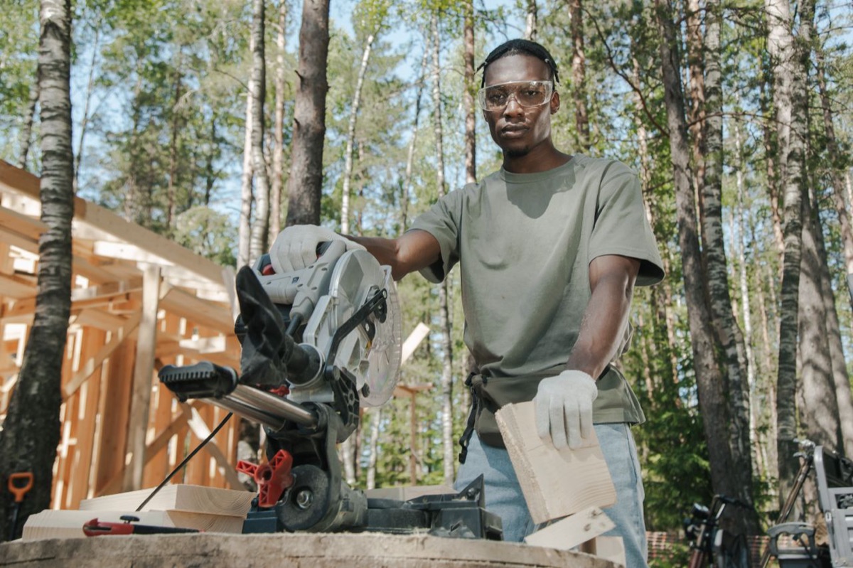 A person using a miter saw at an outdoor framing site