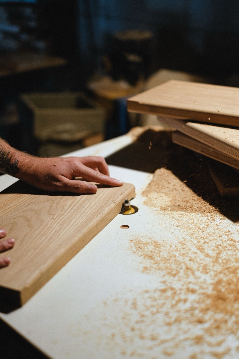 A woodworker feeding a board across a router table