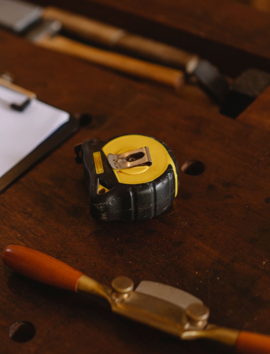 A tape measure resting on a workbench beside a clipboard