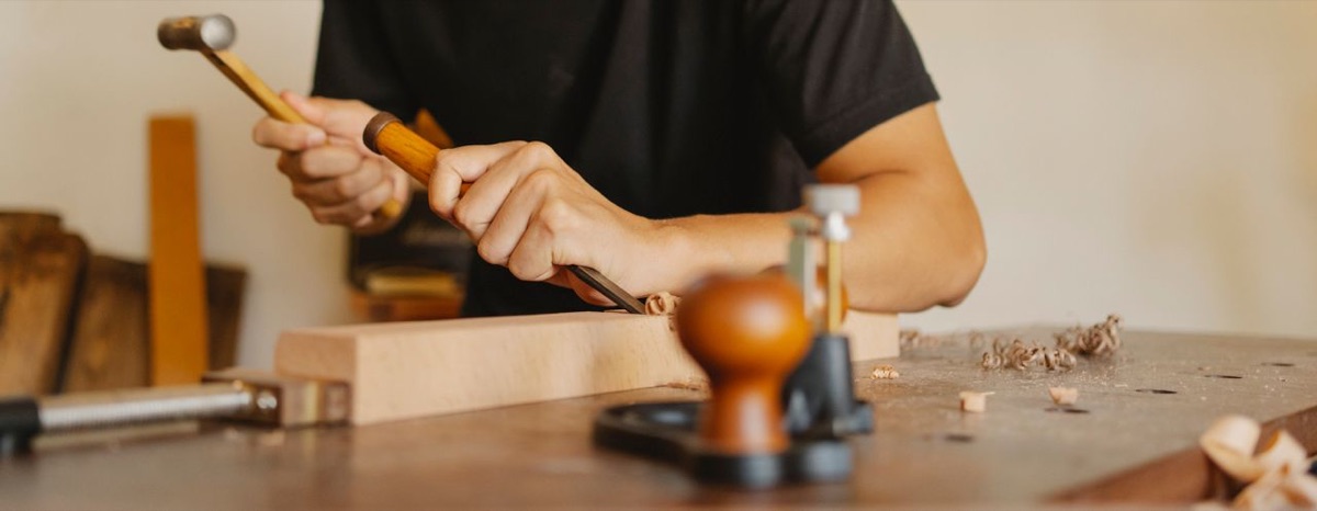 A woodworker working at a bench with hand tools